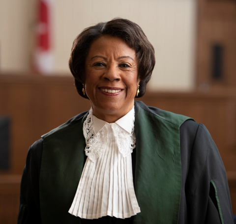 Black woman wearing green, black and white judicial robes.