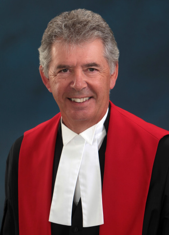 Man with salt-and-pepper hair wearing red, black and white judicial robes.