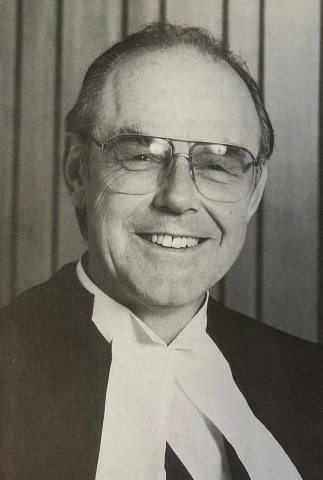 Black and white photo of a man in glasses and judicial robes.