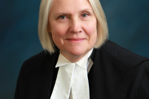 White woman with short white hair, wearing black and white judicial robes.